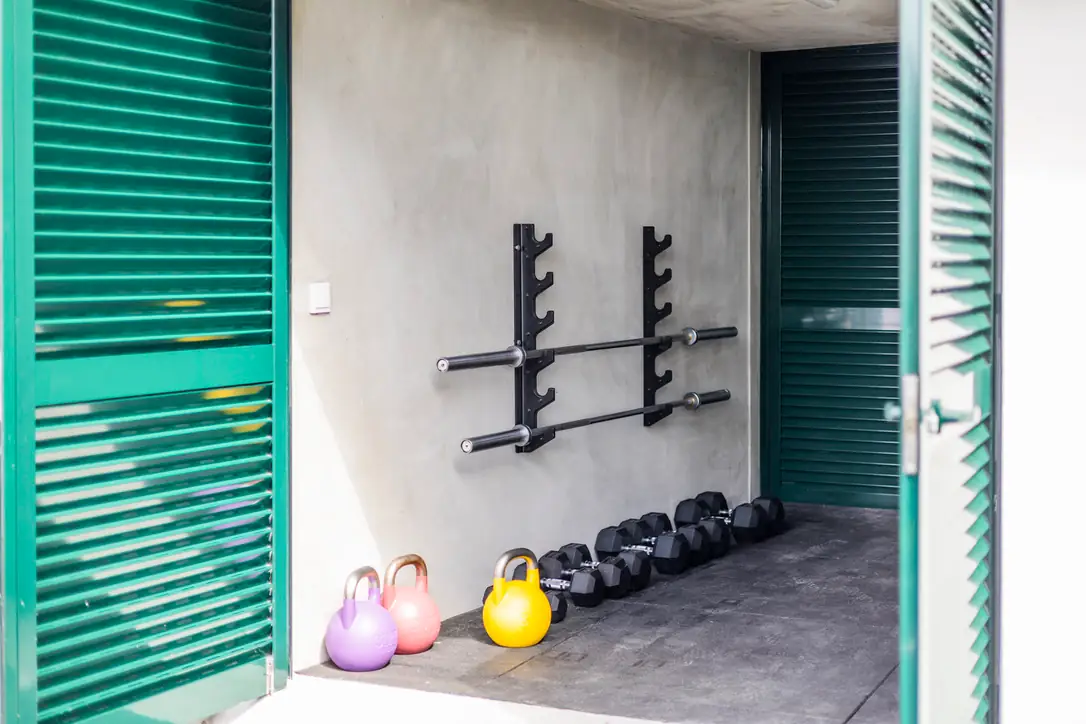 Indoor gym with green shutters, barbell rack and kettlebells, Villa Crossdeira
