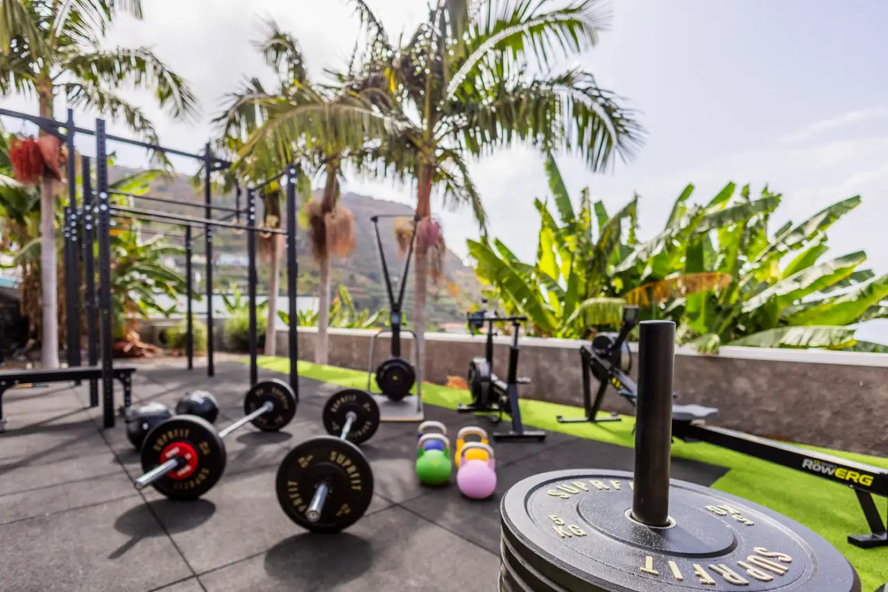 Outdoor gym with Suprfit barbells and plates in front of palm trees, Villa Crossdeira