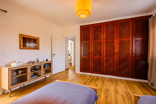 Shared bedroom with carved wooden wardrobe and wooden floor, Villa Crossdeira